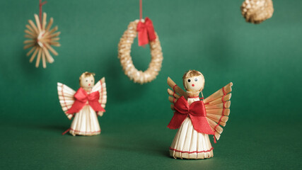 Fototapeta na wymiar Straw Angels and Green Background. Decorations for Christmas and New Year