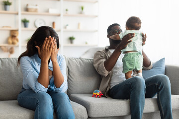 Tired African American mom crying, dad playing with kid - obrazy, fototapety, plakaty