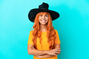 Young woman disguised as witch isolated on blue background keeping the arms crossed in frontal position