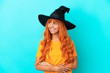 Young woman disguised as witch isolated on blue background happy and smiling