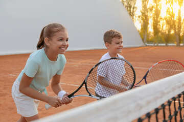 Happy children playing tennis on court outdoors - Powered by Adobe