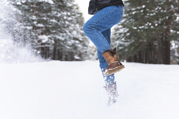 Fototapeta na wymiar Woman wearing sheepskin boots is kicking snow