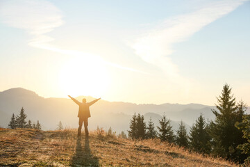 Man enjoying sunrise in mountains, back view. Space for text