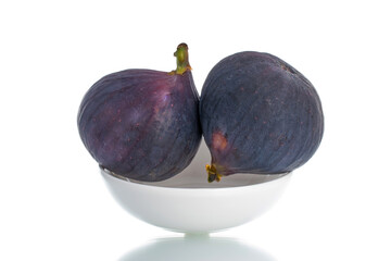 Two organic sweet figs with ceramic dishes, close-up, isolated on white.