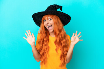 Young woman disguised as witch isolated on blue background counting ten with fingers
