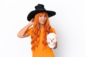 Young mixed race woman disguised as witch holding a skull isolated on white background having doubts