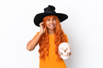 Young mixed race woman disguised as witch holding a skull isolated on white background frustrated and covering ears