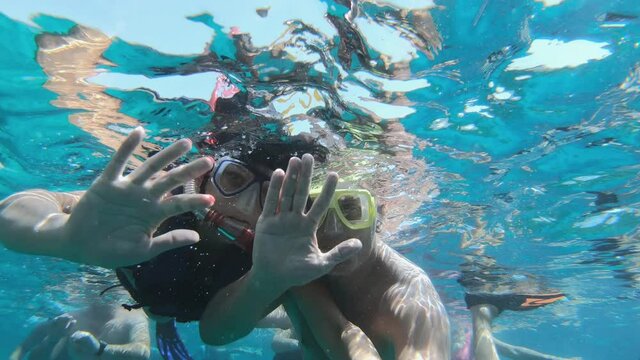 Happy couple in snorkeling mask dive underwater with fishes school in coral reef sea pool. Travel lifestyle, water sport outdoor adventure, swimming lessons on summer beach holidays