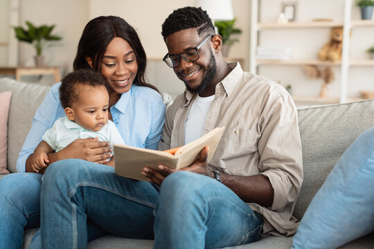 Portrait of happy black family reading book for infant