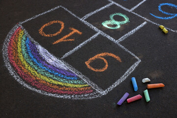Hopscotch drawn with colorful chalk on asphalt outdoors
