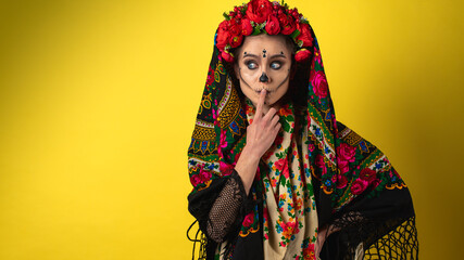 Kalavera Katrina girl shows various emotional gestures to the body, face, in a headscarf, on a yellow background, looks and sideways, a place for an inscription. Dia-de -los -muertos. Day of death.