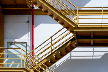 Sunlight and shadow on surface of fire escape outside of the old industrial building