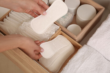 Young woman putting pantyliners into drawer, closeup