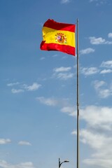 flag of spain on its mast, against the sky waving in a windy day with a street lamp in the background. Hispanic national heritage day