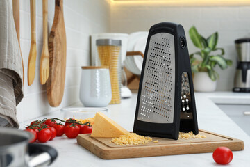 Grater, cheese and cherry tomatoes on kitchen counter