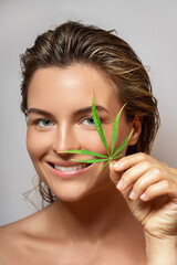 CBD cosmetics concept. Beautiful woman with a cannabis leaf