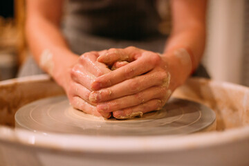 Men's hands are clutching clay on a pottery table. My hands are stained with clay