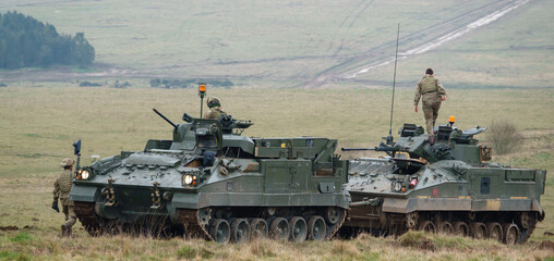 REME soldiers army mechanized recovery vehicle FV512 preparing to tow a stricken Warrior infantry...