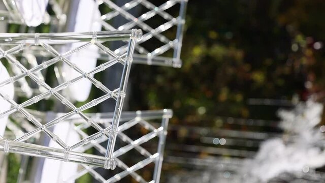 Transparent plastic Chiavori chairs for guests on the street close-up. Autumn wedding ceremony on the street on the green lawn.