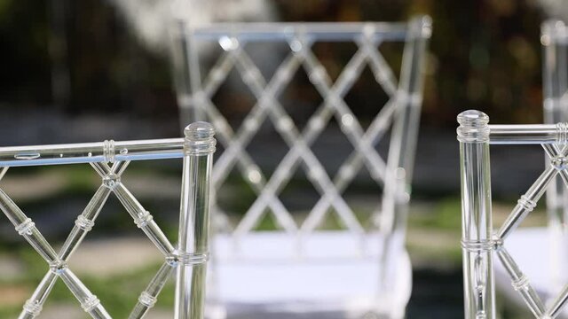 Transparent plastic Chiavori chairs for guests on the street close-up. Autumn wedding ceremony on the street on the green lawn.