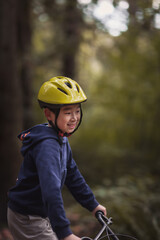 Young boy riding mtb bicyle with helmet on trail off road in forest park so excited and have fun