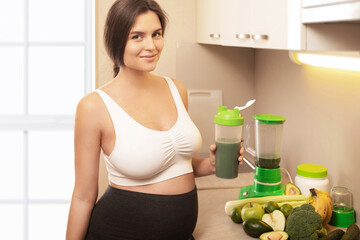 Fototapeta na wymiar Pregnant woman holding shaker with a green protein cocktail