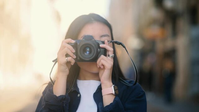 Close up portrait of attractive asian girl tourist with camera standing outdoors in city. Photographer taking pictures. . High quality 4k footage