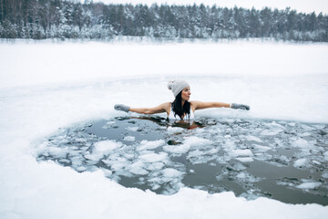 Winter cold swimming. Woman in frozen lake ice hole. Swimmers wellness in icy water. How to swim in...