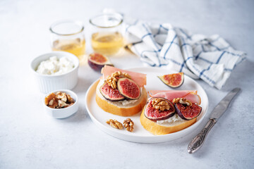 Obraz na płótnie Canvas Figs ricotta prosciutto crostini with fresh figs and walnuts
