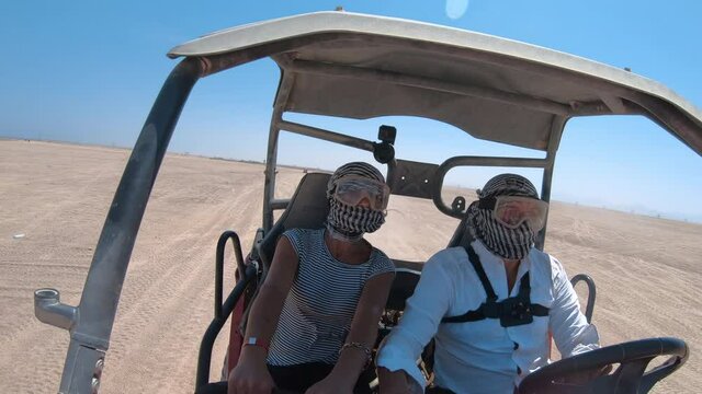 Happy couple bikers driving buggy atv in sand desert safari, pov