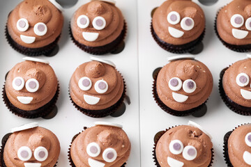 Set of cupcakes in the white gift box. Chocolate cupcake with brown cream cheese top decorated with mastic smiley face