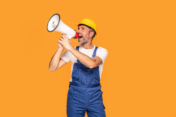 Handsome happy construction worker shouting loud by megaphone with smile and positive emotions on his face.