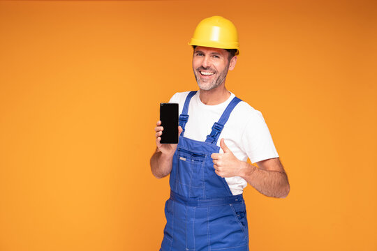 Smiling Construction Worker Showing Cellphone Empty Screen to the camera.