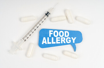 On a white background pills, a syringe and a blue plate with the inscription - FOOD ALLERGY