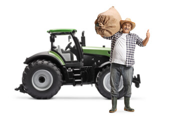 Full length portrait of a happy mature farmer gesturing thumbs up in front of a tractor