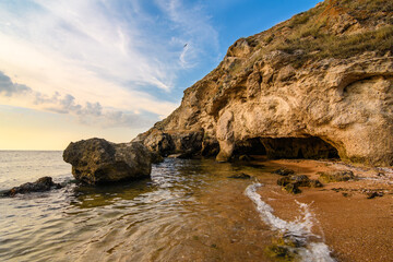Fototapeta na wymiar Rocky seashore with small caves. Seascape 