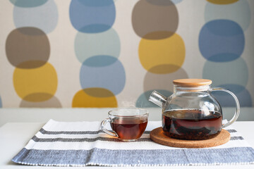 Transparent cup and teapot on the kitchen table.