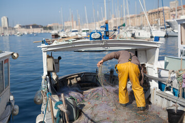 Le pêcheur sur le bateau de pêche lié par le marché au poisson de Marseille le Vieux Port