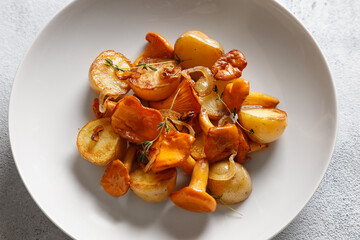 fried potatoes with chanterelles mushrooms on a white plate on a white background for dinner