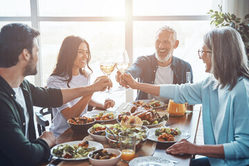Happy multi-generation family toasting each other and smiling while having dinner together