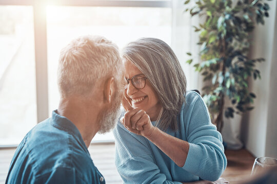 Playful Senior Couple Sitting Face To Face And Smiling While Spending Time At Home