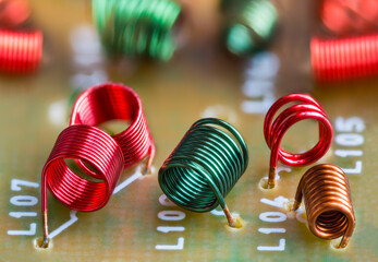 Electronic air-core inductors on beige printed circuit board detail. Closeup of colored spiral...