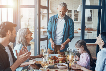 Happy multi-generation family communicating and smiling while having dinner together