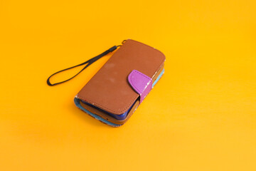 Old used brown phone case isolated on orange background