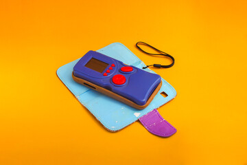 Blue retro electronic portable game console on orange background. Old school game stock photo