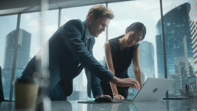 Portrait of Successful Corporate CEO and Investment Manager Talking, Using Laptop Computer while Standing in City Office. Two Businesspeople Celebrate Successful Deal with a Fist Bump.