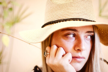 Close-up portrait of a blond haired young woman wearing straw hat
