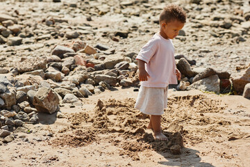 Minimal full length portrait of cute baby boy walking in sand on beach, copy space