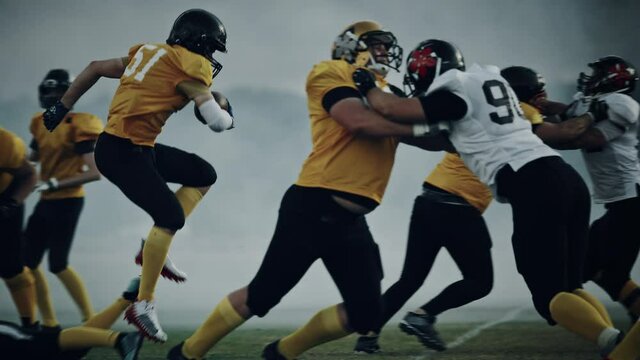 American Football Field Two Teams Compete: Successful Player Jumping Over Defense Running to Score Touchdown Points. Professional Athletes Compete for the Ball, Tackle, Fight for Championship Victory