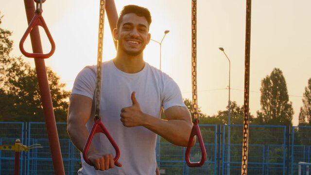 Sporty strong muscular Arab man recommends healthy lifestyle. Young energetic millennial Middle Eastern Indian athletic guy showing thumbs up gesture, happy with workout, effective exercise equipment